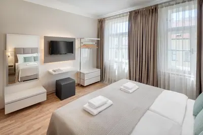 a white hotel room with a bed and a television at Louren Apartments in Prague