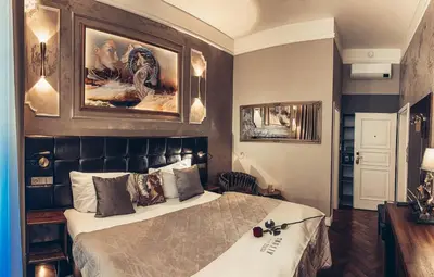 a bedroom with a large bed and paintings on the wall at Alfons Boutique Hotel in Prague