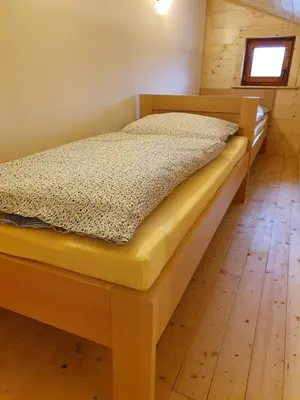 a bed in a bedroom with a wooden floor at Sport-hotel Šibeniční vrch in Mnichovice