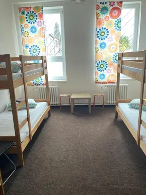 a room with three bunk beds and two windows at Hostel Praha Ládví in Prague