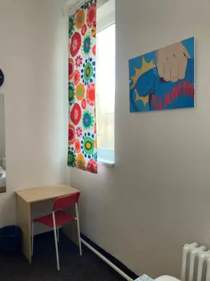 a room with a table and a painting on the wall at Hostel Praha Ládví in Prague