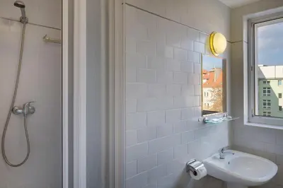 a white bathroom with a sink and a shower at Hotel Otar in Prague