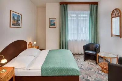 a hotel room with a bed and a chair at Hotel Otar in Prague