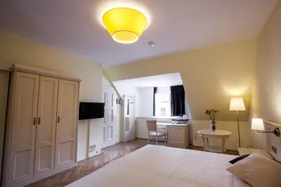 a bedroom with a bed and a desk with a yellow light at Tyn Yard Residence in Prague