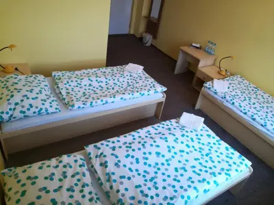 a room with three beds with blue and white sheets at Hotel Modrá hvězda Sadská in Sadská