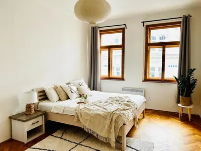 a white bedroom with a bed and two windows at Big family apartment in Prague