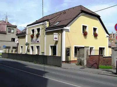 a yellow building with flower boxes on the windows at Penzion Coupe in Příbram