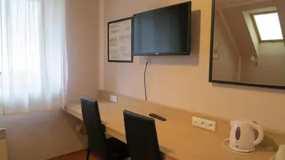 a room with a desk with two chairs and a flat screen tv at Penzion Coupe in Příbram