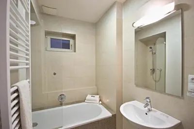 a bathroom with a tub and a sink and a mirror at River View Residence in Prague