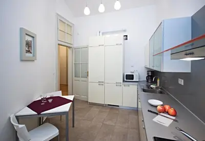 a kitchen with white cabinets and a table and a counter at River View Residence in Prague