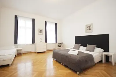 a white bedroom with a bed and two windows at Prague Central Residence in Prague