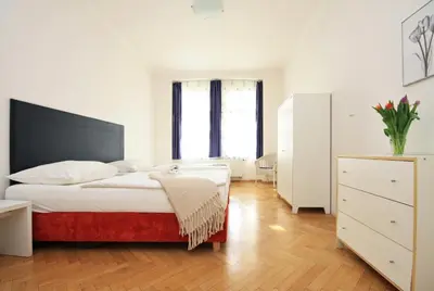 a white bedroom with a bed and a dresser at Prague Central Residence in Prague