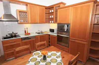 a kitchen with wooden cabinets and a table with flowers on it at Prague Central Residence in Prague