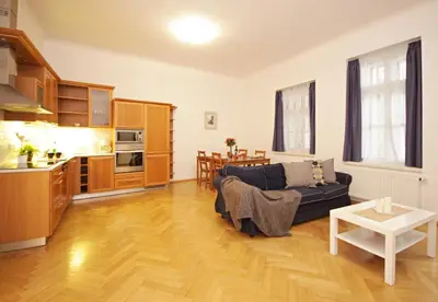 a living room with a blue couch and a kitchen at Prague Central Residence in Prague