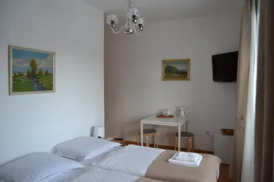 a white bedroom with a bed and a table at Pension Nika in Prague