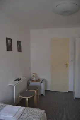 a room with two beds and a table and a door at Pension Nika in Prague