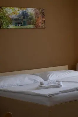 a bed with white sheets and a painting on the wall at Pension Fontana in Poděbrady