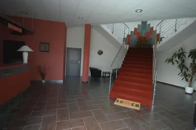 a hallway with a staircase in a building with red walls at Toscca in Čelákovice