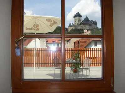 a window with a view of a balcony with an umbrella at Pension a Restaurace Vyhlídka in Karlštejn