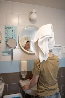 a woman with a towel on her head standing in a bathroom at Prague Dream Hostel in Prague