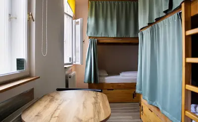 a room with a wooden table and a bunk bed at Prague Dream Hostel in Prague