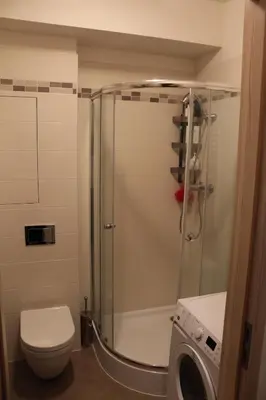 a bathroom with a shower with a toilet and a washing machine at Big Apartment 291 - Rezidence Eliska Prague 9 in Prague
