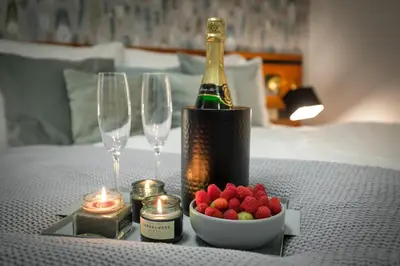a table with a bottle of champagne and a bowl of fruit at 4 Elements Apartments in Prague