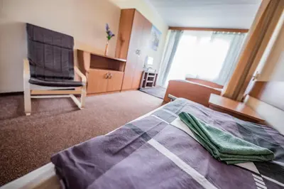 a hotel room with a bed and a chair at Hotel Penzion Rohožník in Prague