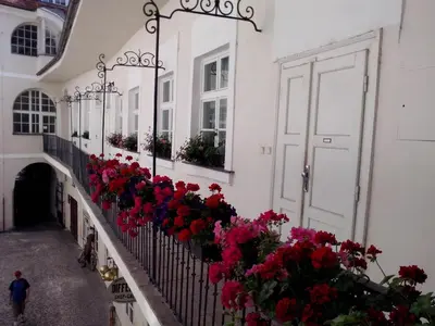 a balcony with red flowers on a white building at Apartments Týnská 7 in Prague