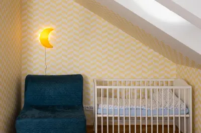a crib and a chair in a room at Veleslavin Apartments in Prague