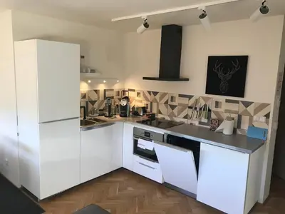 a kitchen with white cabinets and a black counter top at Veleslavin Apartments in Prague