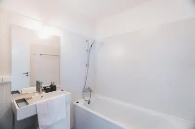 a white bathroom with a tub and a sink at Veleslavin Apartments in Prague