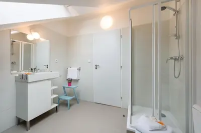 a white bathroom with a shower and a sink at Veleslavin Apartments in Prague