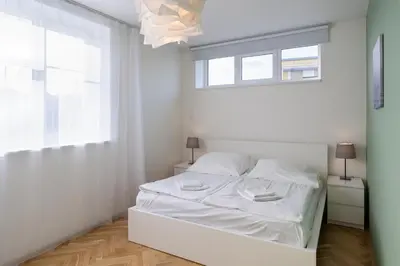 a white bedroom with a white bed and a window at Veleslavin Apartments in Prague