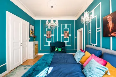 a bedroom with blue walls and a bed with colorful pillows at Glamour Frida apartment in Prague