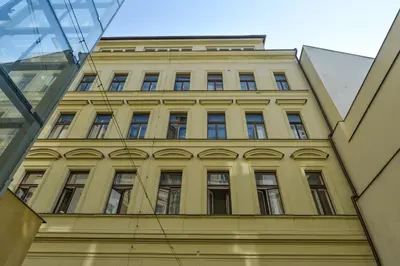 a yellow building in front of a glass building at Glamour Frida apartment in Prague