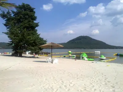 a beach with an umbrella and boats on the water at Kamenný dům Bezdědice-Máchův kraj in Bezdědice