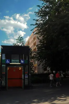a gas station with two people walking in front of it at Panorama Prague Castle with Terrace in Prague