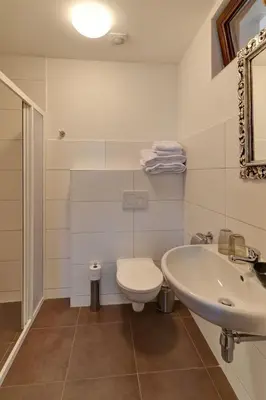 a white bathroom with a toilet and a sink at Penzion Na Letním bytě in Kouřim