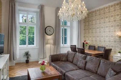 a living room with a couch and a table and a clock at Mikulášská - Old Town Square View Residence in Prague