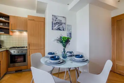 a white kitchen with a white table and chairs at Prague 1 SUNNY APT with terrace by Michal&Friends in Prague