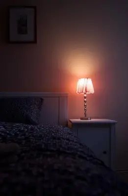 a lamp sitting on a table next to a bed at NOT POSSIBLE TO BOOK Apartment Vltavska F in Prague