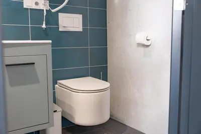a bathroom with a white toilet and blue tiles at Penzion Lesni in Milovice