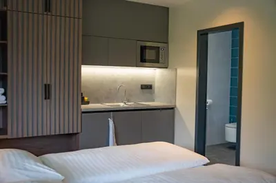 a bedroom with a bed and a kitchen with a sink at Penzion Lesni in Milovice
