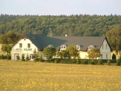 a large white house with a field in front of it at Hotel Kolonie in Křivoklát