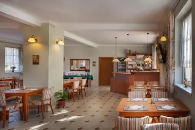 a restaurant with wooden tables and chairs in a room at Hotel Kolonie in Křivoklát