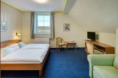 a hotel room with a bed and a chair and a desk at Hotel Kolonie in Křivoklát