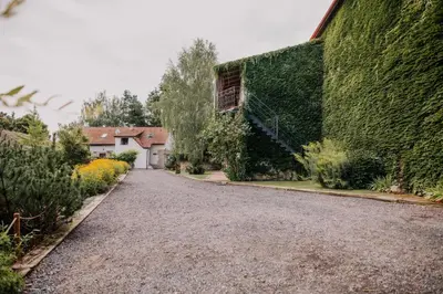 a gravel driveway next to a building with a green wall at Hotel Lony in Mochov