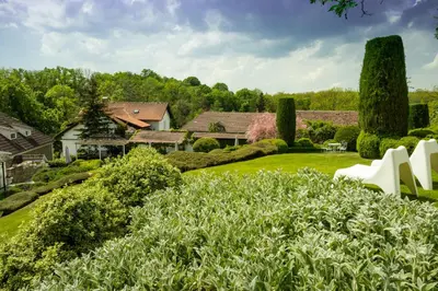 a garden with white chairs and bushes at Family Hotel Okoř in Okoř
