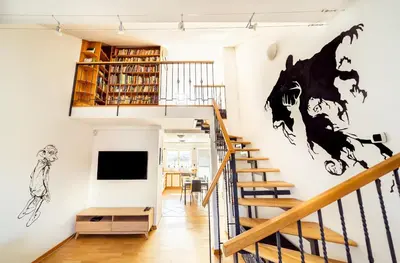 a living room with a staircase and a tv on the wall at 4BR 3BATH BALCONY central Harry Potter penthouse in Prague
